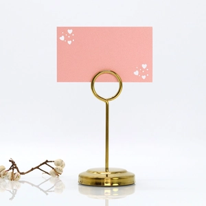Close-up of golden heart place card holder with a pink card and minimalist dried flower decor