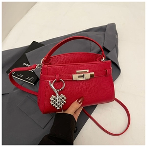 Detail of red litchi grain leather trapezoid bag with silver buckle and heart charm