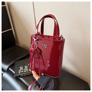 Detail of burgundy patent leather mini handbag with PAN TOR logo and heart pendant charm