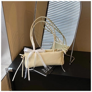 Detailed close-up of cream PU leather handbag featuring white lace bow and side drawstring
