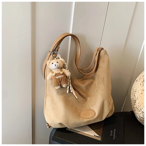 Detail of camel suede tote bag with cute bear charm and striped scarf decoration
