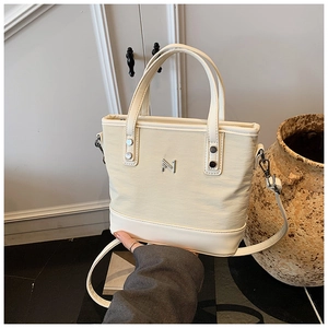 Close-up of beige canvas tote bag with leather straps and metallic logo detail