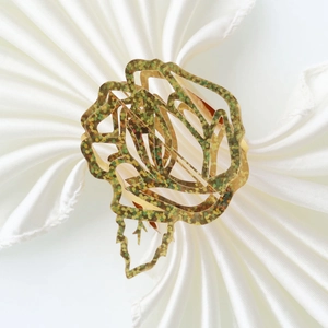 Detailed close-up of a golden rose napkin ring with glitter finish on white fabric