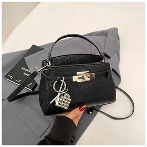 Close-up of black lychee grain leather bag with silver lock and heart charm detail