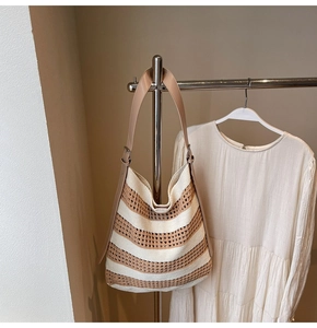 Close-up of woven hollow knit tote bag with contrasting stripes and leather shoulder strap