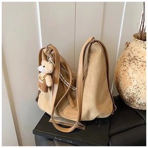 Detail of khaki suede hobo bag featuring logo patch and a cute brown bear charm