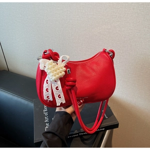 Dettaglio borsa rossa in pelle martellata con ciondolo a cuore e pizzo chic