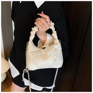 Detailed view of cream PU leather handbag with decorative pearl lace bow and silver chain