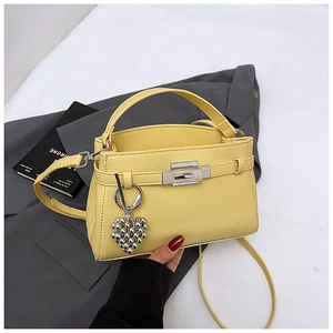 Close-up of yellow litchi leather bag with silver turn-lock and heart bead charm