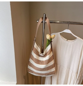Detailed view of woven straw tote bag with striped pattern and premium leather shoulder strap