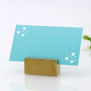 Close-up of golden heart place card holder with decorative blue paper on white surface