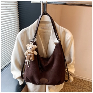 Detailed macro of brown suede tote bag with a cute teddy bear fashion pendant
