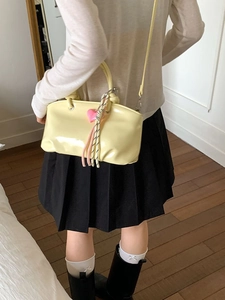 Minimalist light yellow patent leather bucket bag with wave edge and heart charm accessory