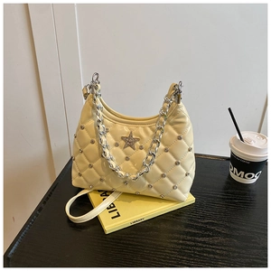 Détail du sac matelassé crème avec breloque étoile argentée et bandoulière à chaîne