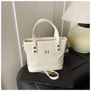 Detailed close-up of cream PU leather bucket bag with metal logo and adjustable strap
