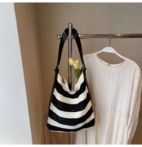 Detail of hollow-out knit pattern and black leather strap on striped tote bag