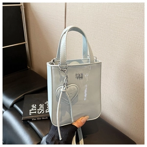 Detail of light blue patent leather mini tote with heart pendant and metal logo
