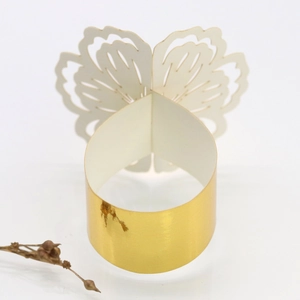 Macro detail of gold butterfly napkin ring featuring laser-cut floral wings and glossy finish