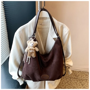 Detail of dark brown faux suede tote bag with leather straps and cute bear pendant