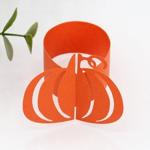 Macro view of orange laser-cut paper napkin ring featuring a Halloween pumpkin design