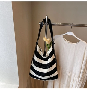 Detail of black and white striped knit hobo bag with wide leather strap and metal ring