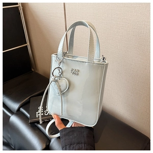Detail of light blue patent leather mini tote bag with heart charm and adjustable strap