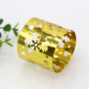 Detail of gold snowflake napkin ring with intricate laser cutouts on reflective surface