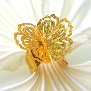 Detail of laser-cut gold glitter butterfly napkin ring on white satin fabric decoration