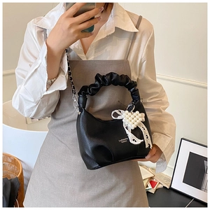Detail of black pebbled leather underarm bag with pearl bow charm and chain strap