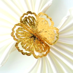 Macro shot of 3D golden hollow flower napkin ring with glitter on white satin fabric