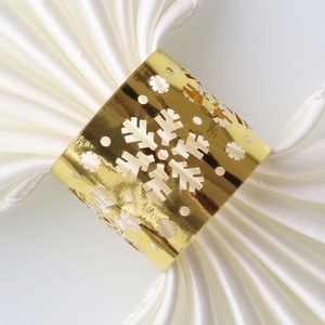 Close-up of golden snowflake napkin ring with mirrored finish on a white satin cloth