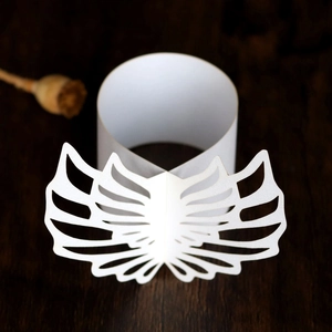 Macro shot of laser-cut white pearlescent paper napkin ring with angel wing design