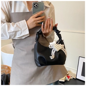 Detail of black faux leather bag with white lace bow and pearl heart decoration