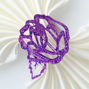 Close-up of elegant purple glitter rose napkin ring on a white satin fabric background