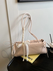 Pink faux leather underarm bag with lace bow decoration on a vintage wooden table