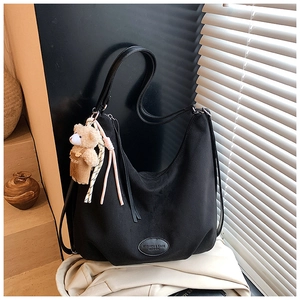 Detail of black canvas tote bag with leather logo patch and cute plush bear accessory