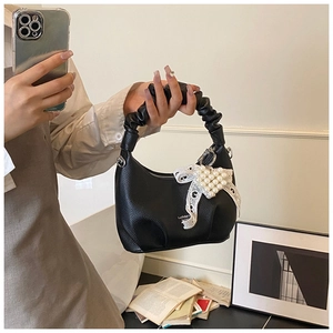 Detail of black lychee leather underarm bag with lace bow and pearl heart pendant