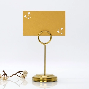 Close-up of golden heart place card holder with spiral clip and decorative card