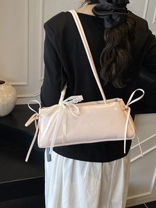 Minimalist beige underarm bag with large white lace bow and glossy ribbon detail