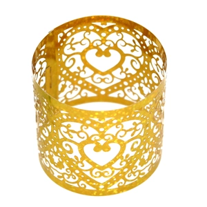 Close-up of golden hollow heart napkin ring featuring elegant filigree patterns