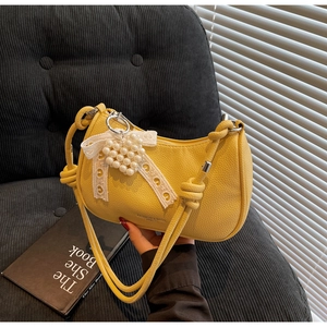 Dettaglio della borsa hobo in pelle gialla con fiocco in pizzo bianco e ciondolo cuore