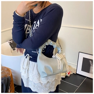 Detail of light blue crescent bag with pearl heart, lace bow, and ruffled handle