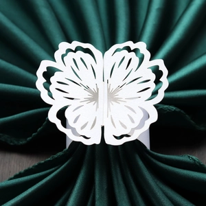 Macro shot of laser-cut white butterfly napkin ring on elegant dark green fabric