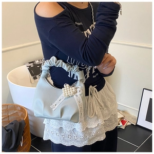 Detail of light blue wrinkled underarm bag with lace bow and pearl heart charm decor