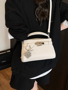White litchi pattern trapezoid Kelly handbag with grape charm and slim crossbody strap