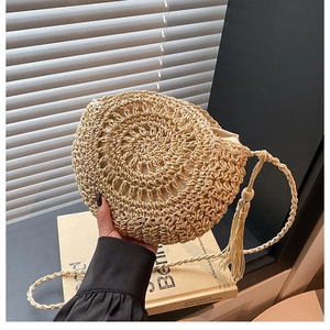 Dettaglio borsa circolare beige intrecciata a mano con frange e tracolla intrecciata