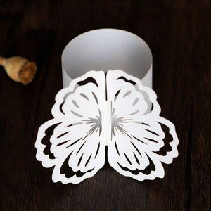 Close-up of laser-cut white paper butterfly napkin ring with elegant hollow patterns