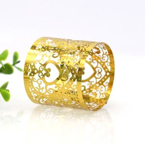 Detail of golden heart napkin ring with laser-cut hollow patterns and glitter finish