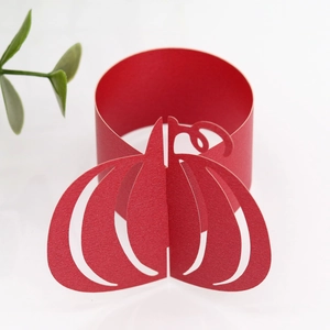 Detail of red hollow paper pumpkin napkin ring with intricate laser-cut textures