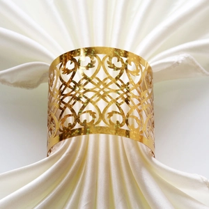 Detailed macro view of a gold openwork napkin ring with intricate heart and scroll patterns